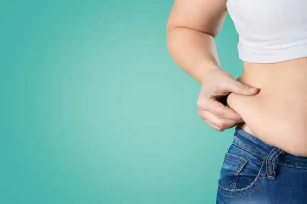 Image of woman pinching her love handles to show weight gain Byfleet